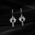 Pair of silver cross earrings with black stones on a dark background