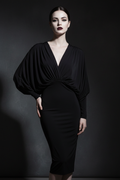 Woman wearing the black Noir Batwing Midi Dress against a dark background