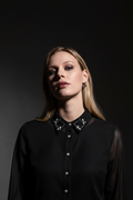 Woman wearing a black blouse with a decorative collar against a dark background
