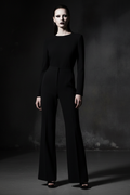 Person wearing a black shirt and wide leg pants against a dark background